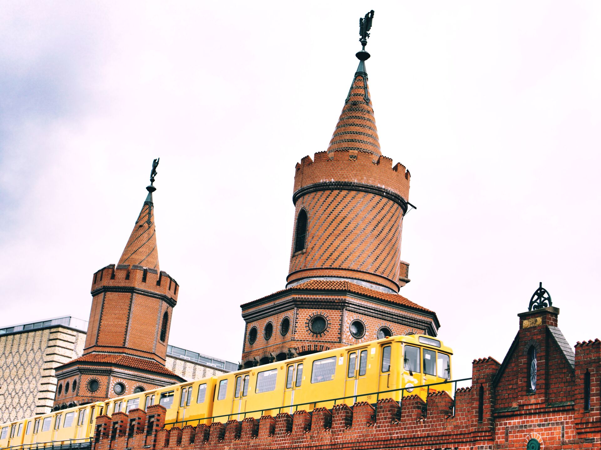 Gelbe U-Bahn fährt über die Oberbaumbrücke mit ihren markanten Backsteintürmen in Berlin.
