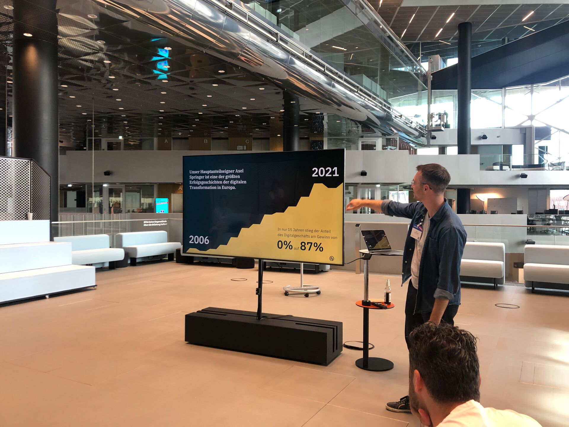 Person hält eine Präsentation mit Diagramm über digitale Transformation im modernen Gebäude.