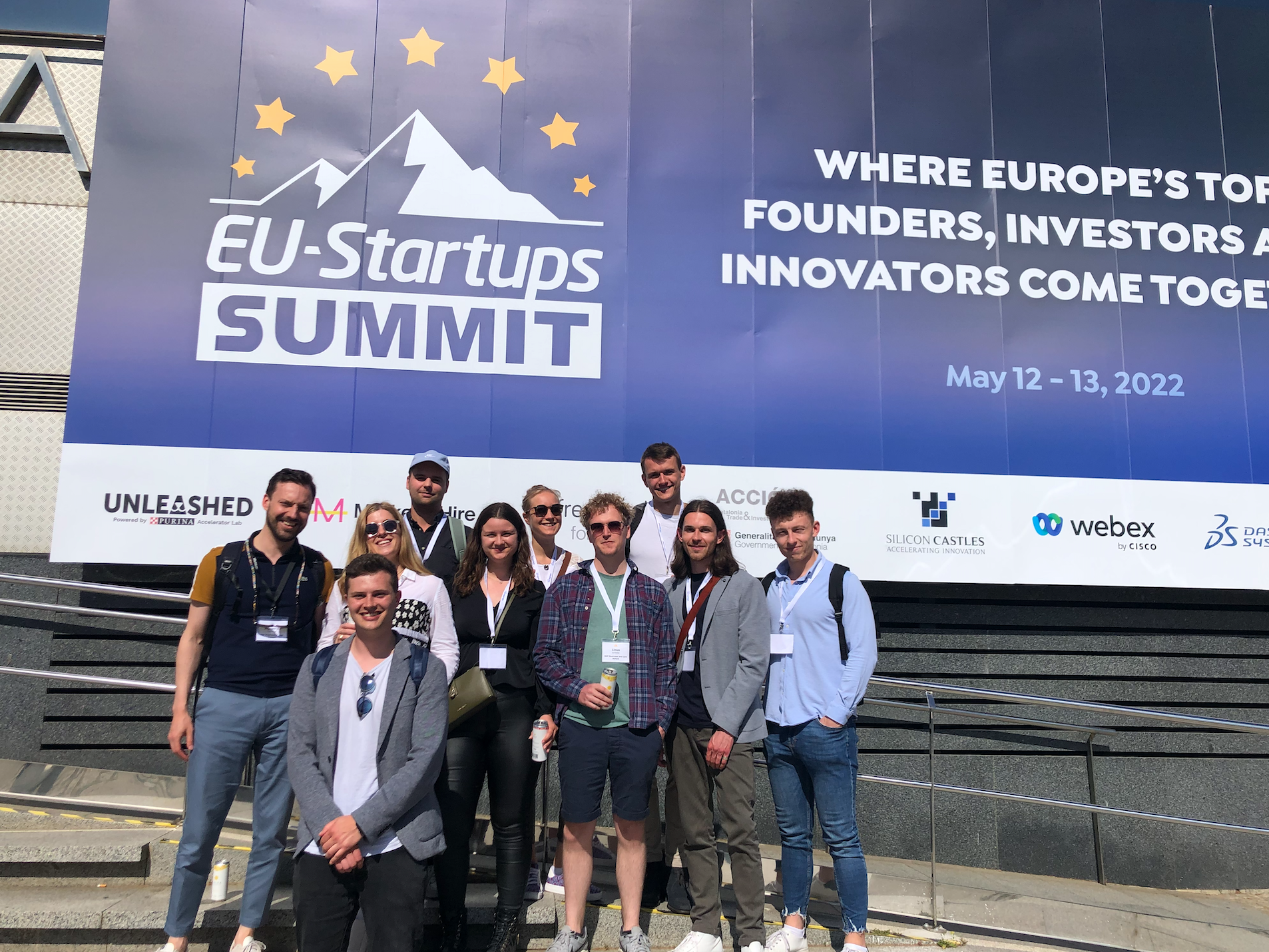 Gruppe von Teilnehmern posiert vor dem großen Banner des EU-Startups Summit 2022.