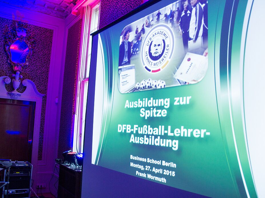 Präsentationsfolie mit dem Titel „Ausbildung zur Spitze – DFB-Fußball-Lehrer-Ausbildung“ bei einer Veranstaltung an der Business School Berlin.