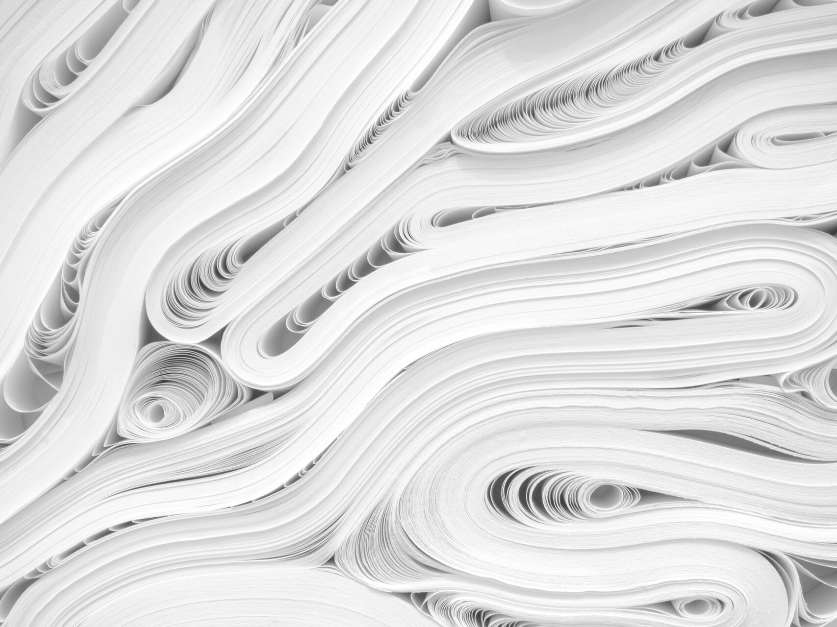 Gestapelte und geschwungene Papierbögen in abstraktem Muster.