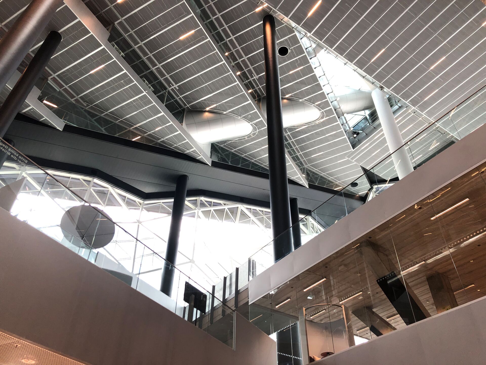 Modernes Gebäudeinnere mit Glasfronten, hohen Decken und futuristischer Architektur.