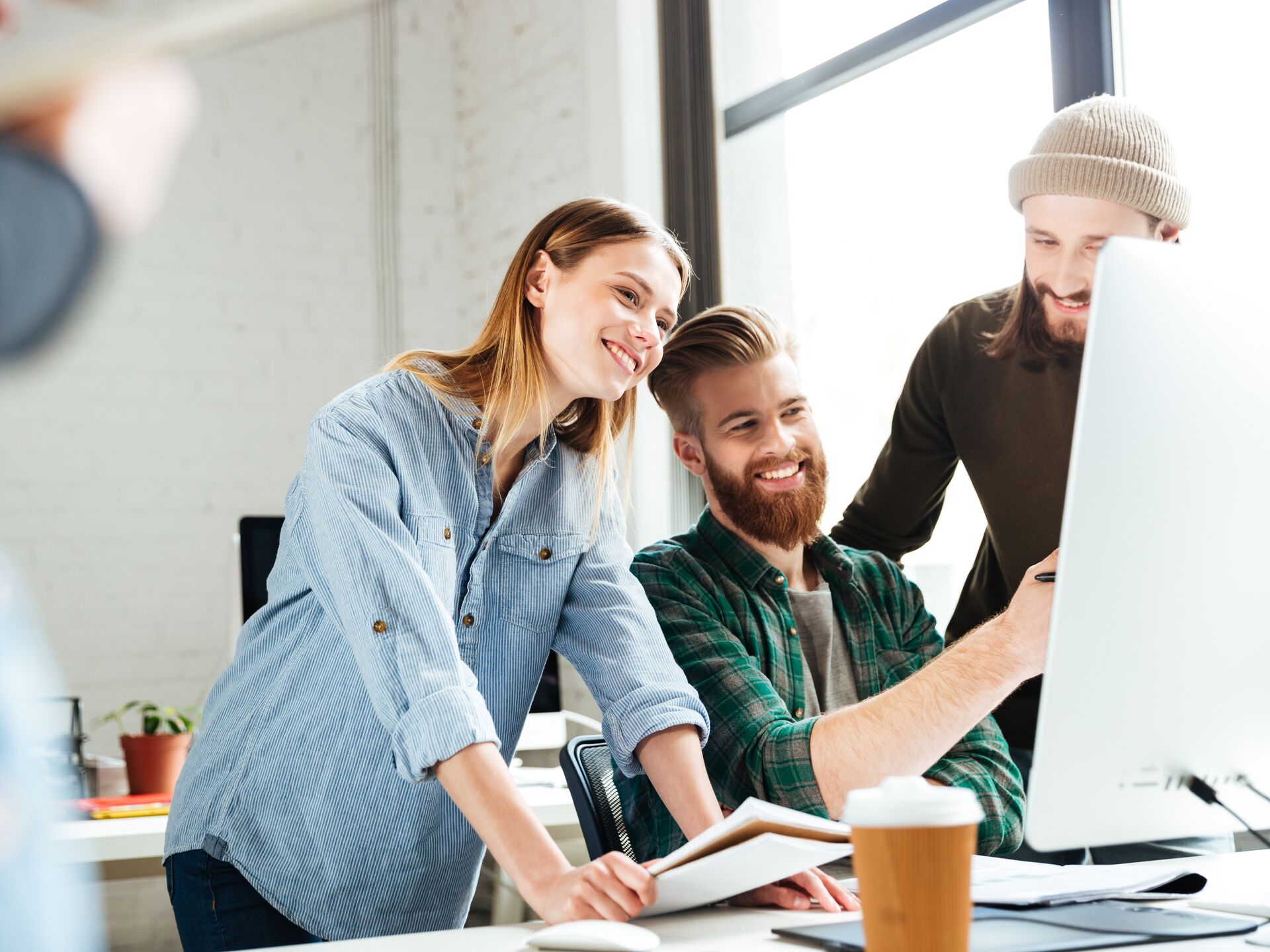 Zwei junge Menschen arbeiten gemeinsam am Laptop und lächeln dabei.