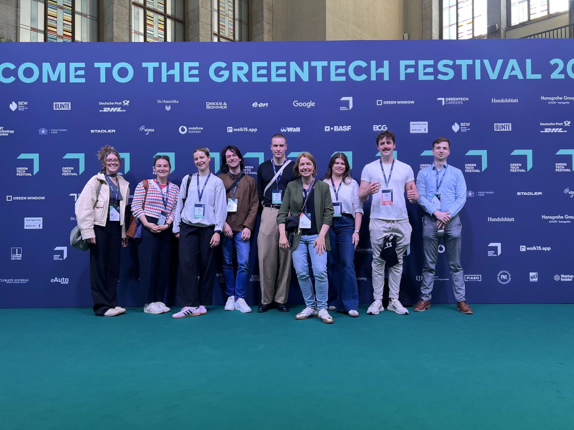 Gruppe von Teilnehmer:innen vor der Sponsorenwand des Greentech Festivals 2024.
